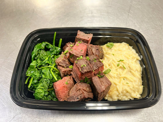 Steak tips over truffled parmesan orzo with sauteed spinach